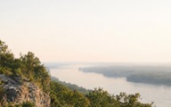 A wooded bluff above the Mississippi south of St. Louis at dawn.