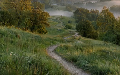 A path through misty hills at sunrise.