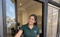 A staff member holds open our front door at 3934 Union Rd, with the number and our logo on the glass.